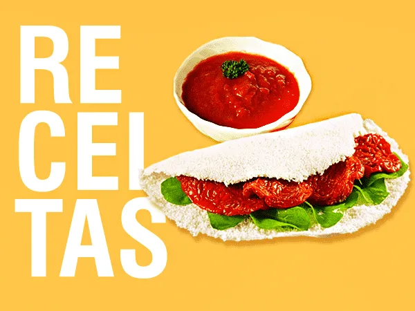 Foto com uma tapioca de tomate seco com agrião ao lado de um pote com molho de tomate dentro. Do lado esquerdo da imagem há o texto "Receitas"
