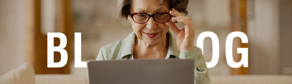 Foto de uma idosa sentada em um sofá olhando o computador com o texto